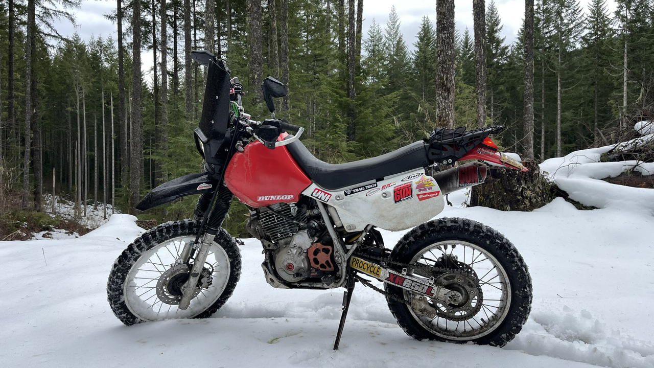 Honda XR650L snowy mountain top woodlands